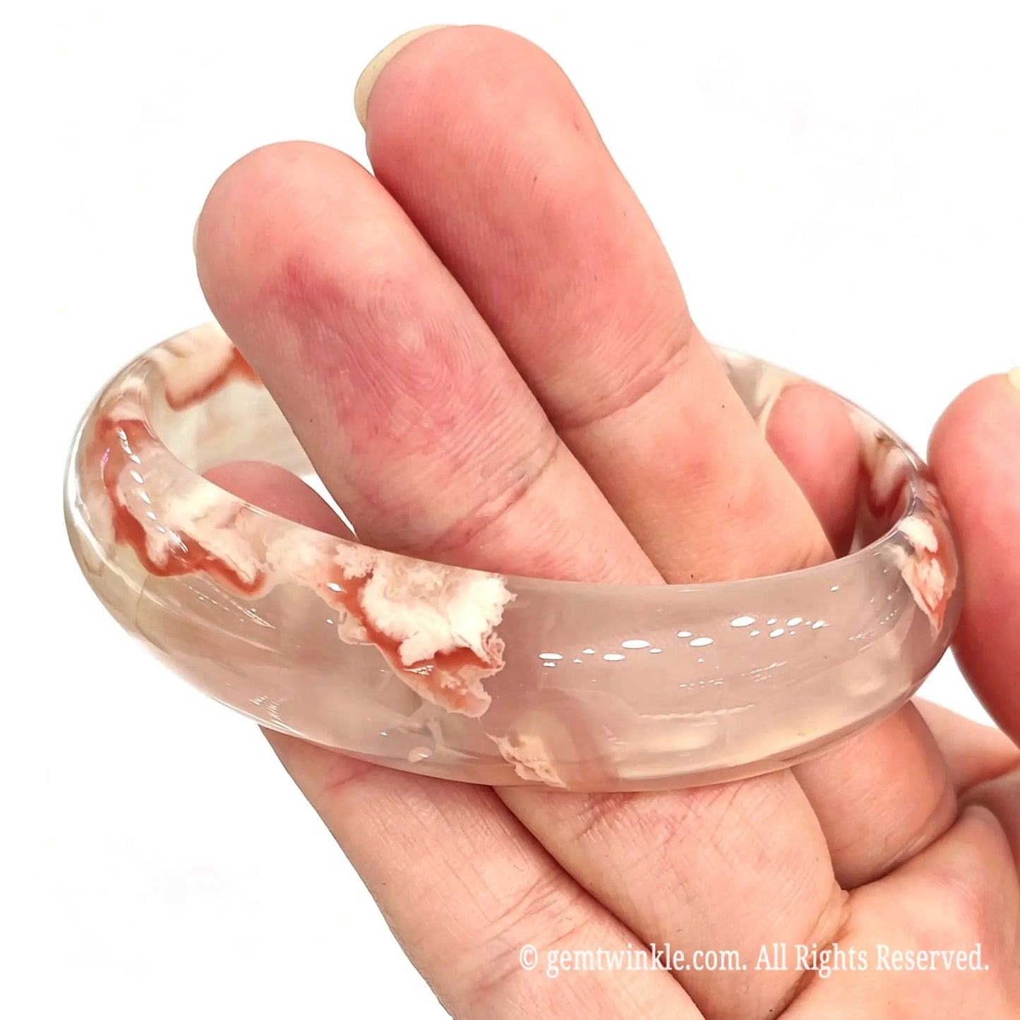 Full cherry blossom agate bangle resting across open fingers displaying natural floral inclusions and icy clarity