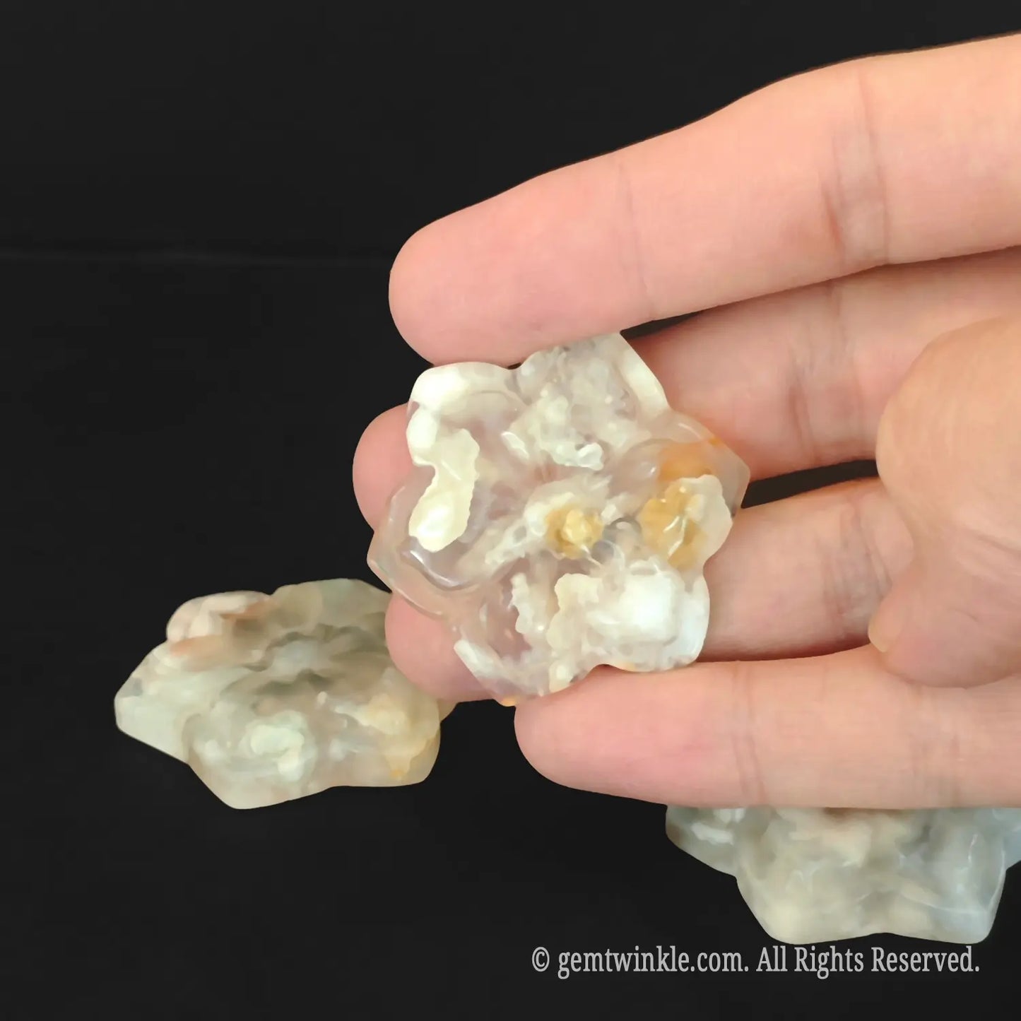 Close up of natural flower agate sakura plate being held to show creamy chalcedony inclusions