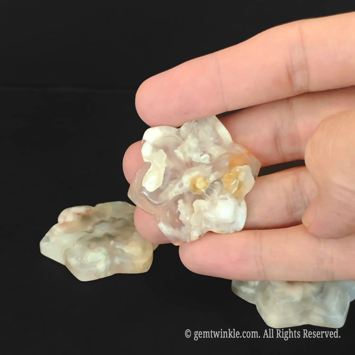 Close up of natural flower agate sakura plate being held to show creamy chalcedony inclusions