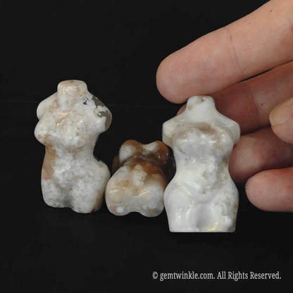 One laying and two standing flower agate female torso crystal carvings with a hand to show textures and sizes for boutique retail