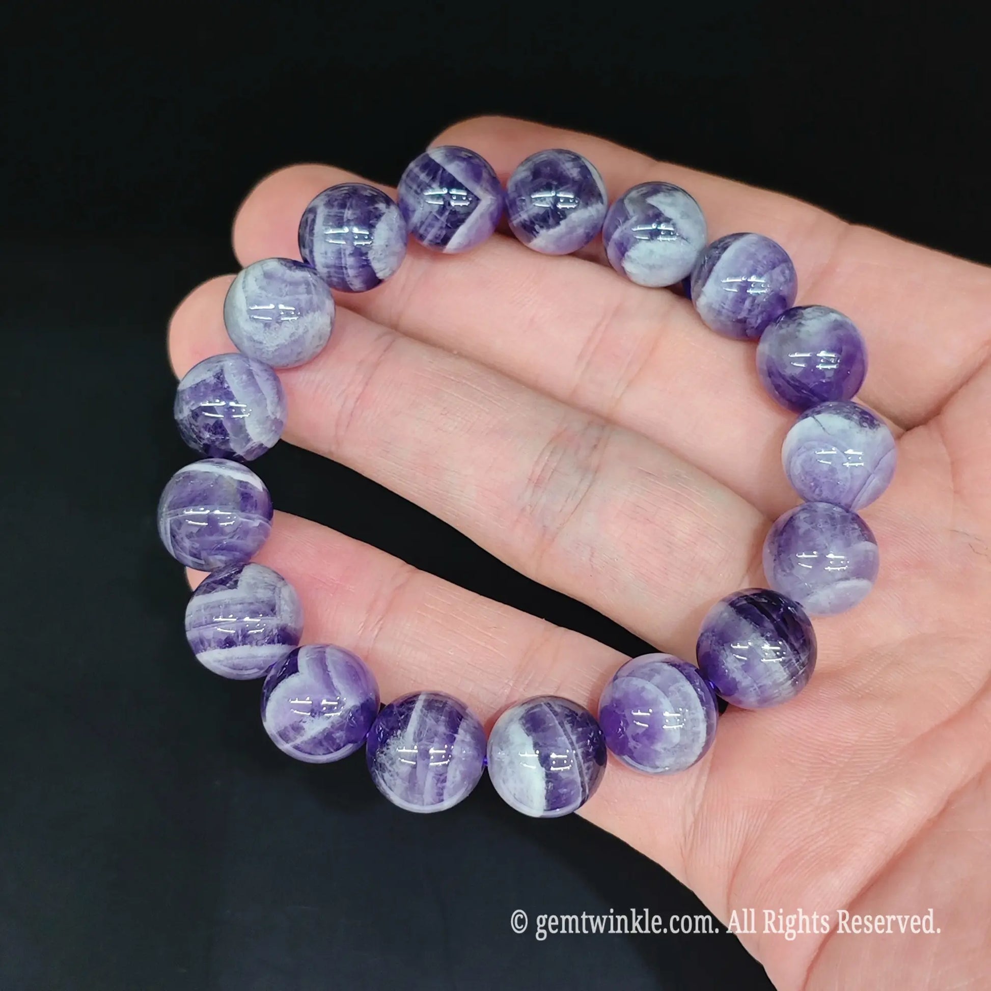 Chevron amethyst round bead bracelet held in hand under studio light showing crisp white quartz banding