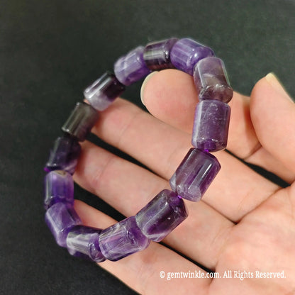 side profile of natural purple amethyst drum bead bracelet on hand showing glossy finish