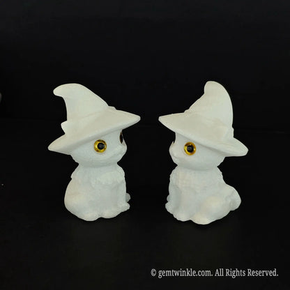Two white marble chibi wizard kitten figurines facing each other in profile showcasing the curves of the pointed witch hats