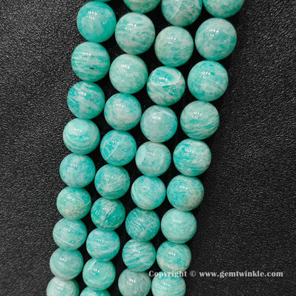 Multiple strands of chunky natural Grade B amazonite large round beads lined up on dark background