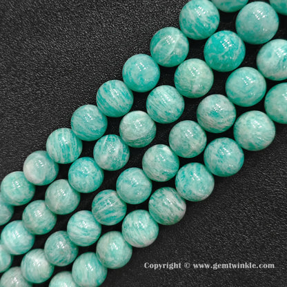 Parallel strands of chunky natural Grade B amazonite large round beads on dark surface