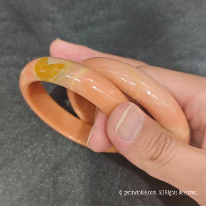 Pair of authentic carved Apricot Quartz bangles displaying warm orange yellow mineral pattern