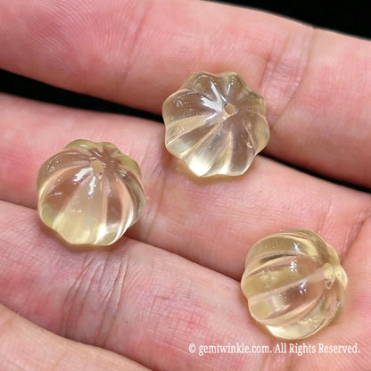 Group preview of three 12mm yellow citrine pumpkin beads on hand showing light transmission
