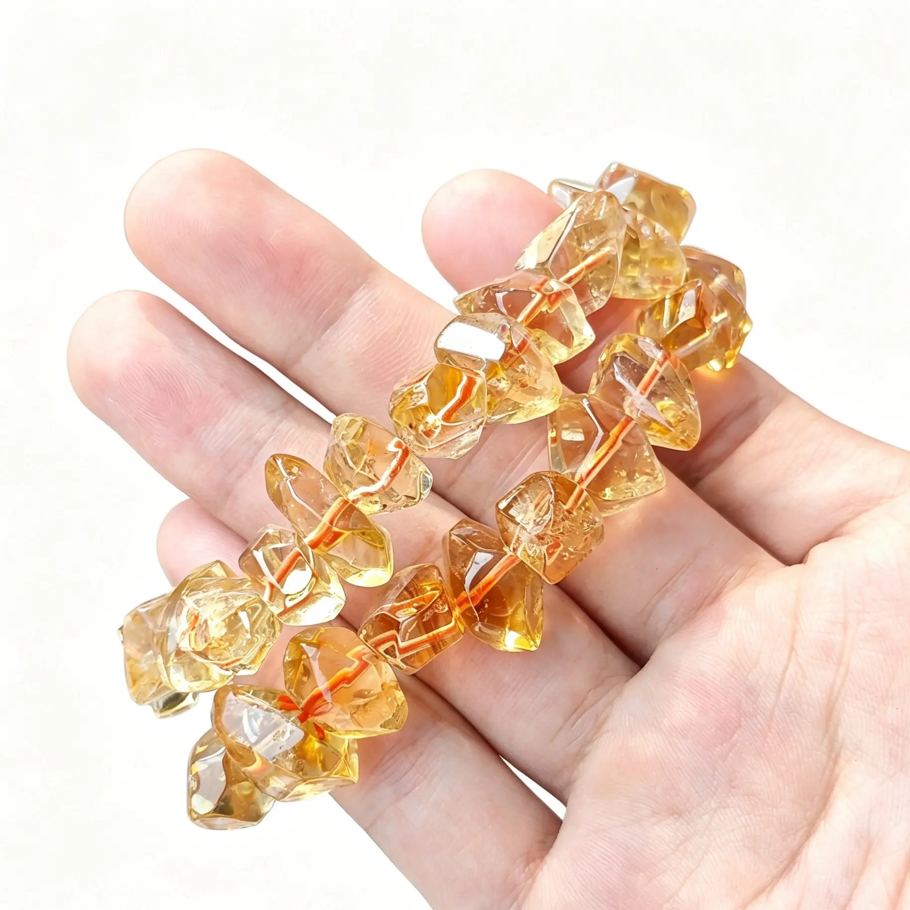 Main view of golden citrine quartz freeform nugget bead stretch bracelets held across open palm showing glassy transparency