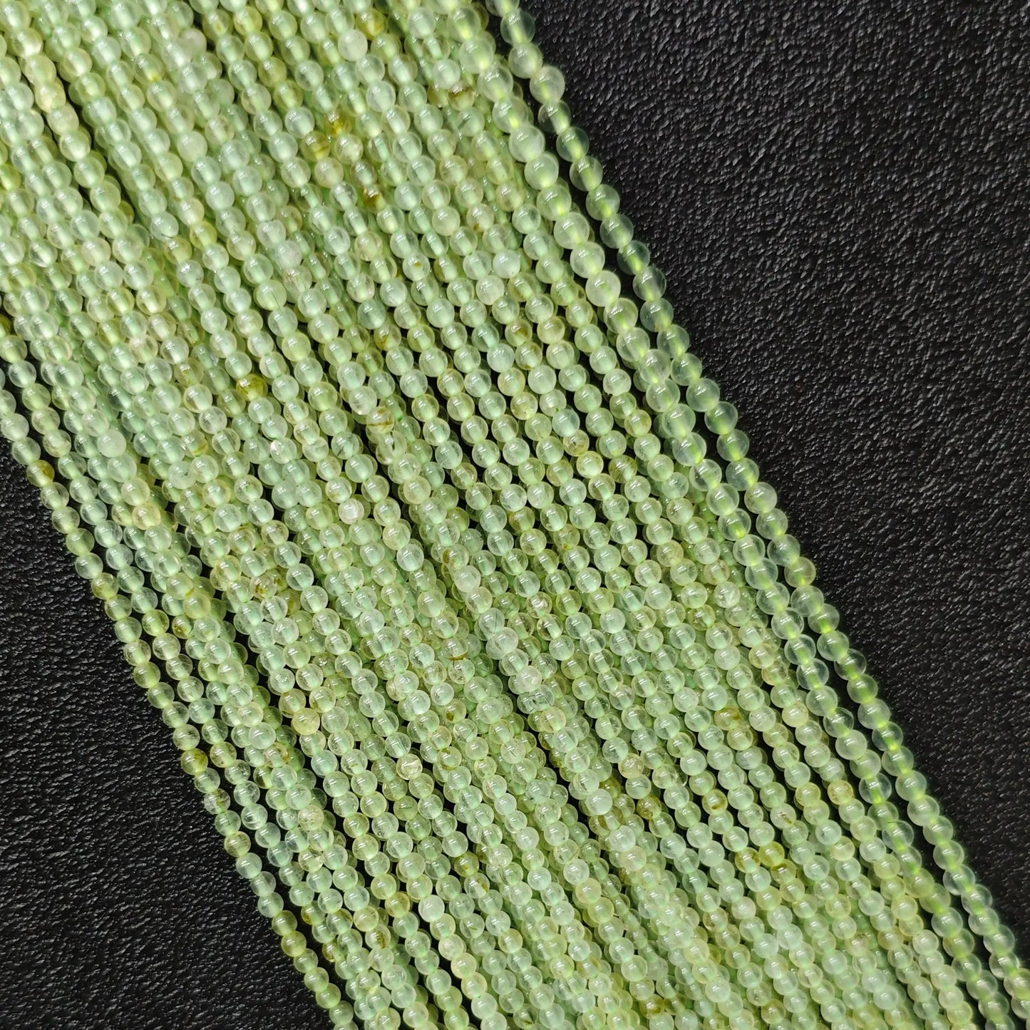Macro closeup of clean prehnite smooth round seed beads 3mm showing translucent green body free of black spots