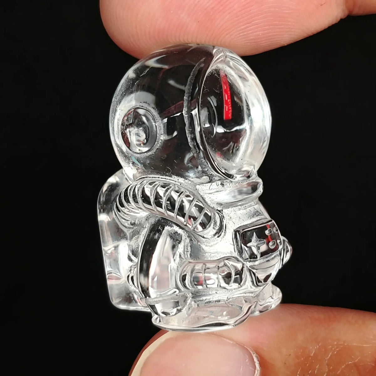 Side view of 30mm clear quartz astronaut carving showing suit tubing and helmet visor held in hand