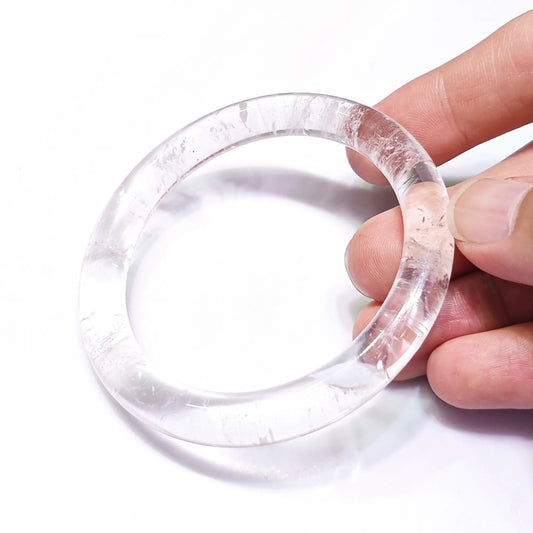 Natural clear quartz bangle B grade with internal ice cracks and cloud inclusions on white background