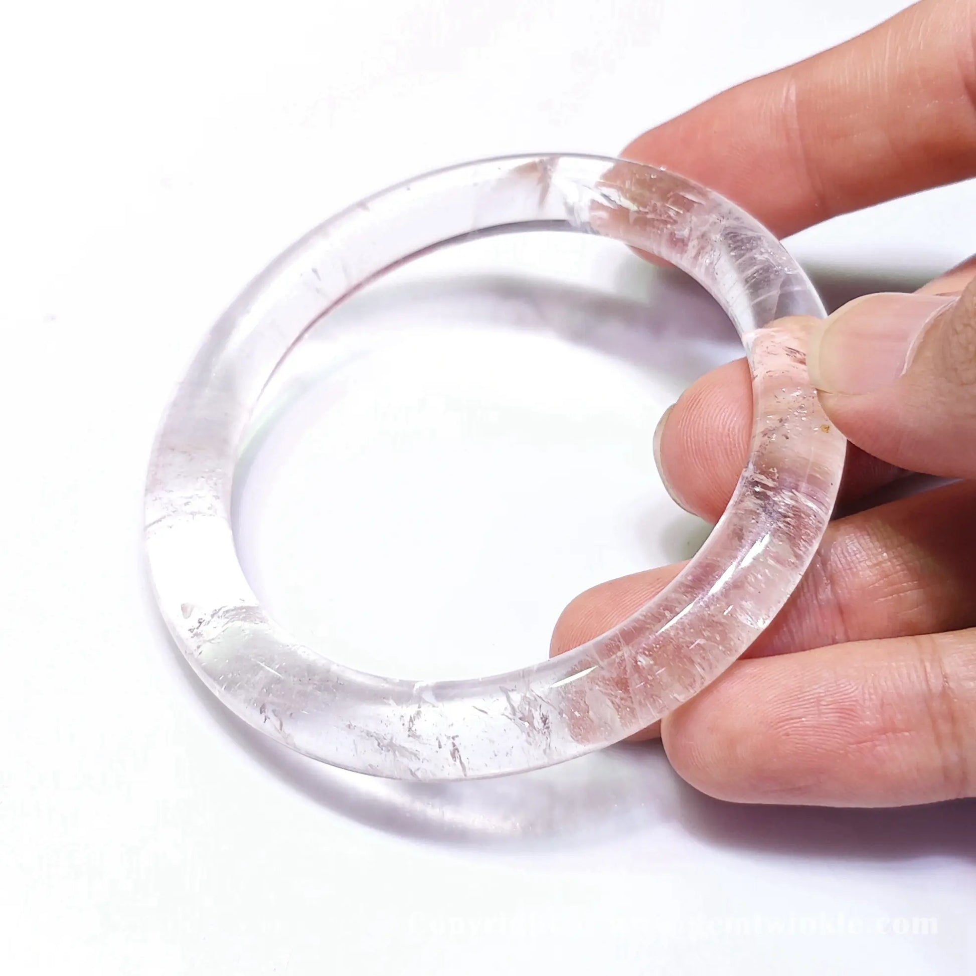 Close up handheld view displaying natural ice crack patterns and light refraction inside quartz bangle