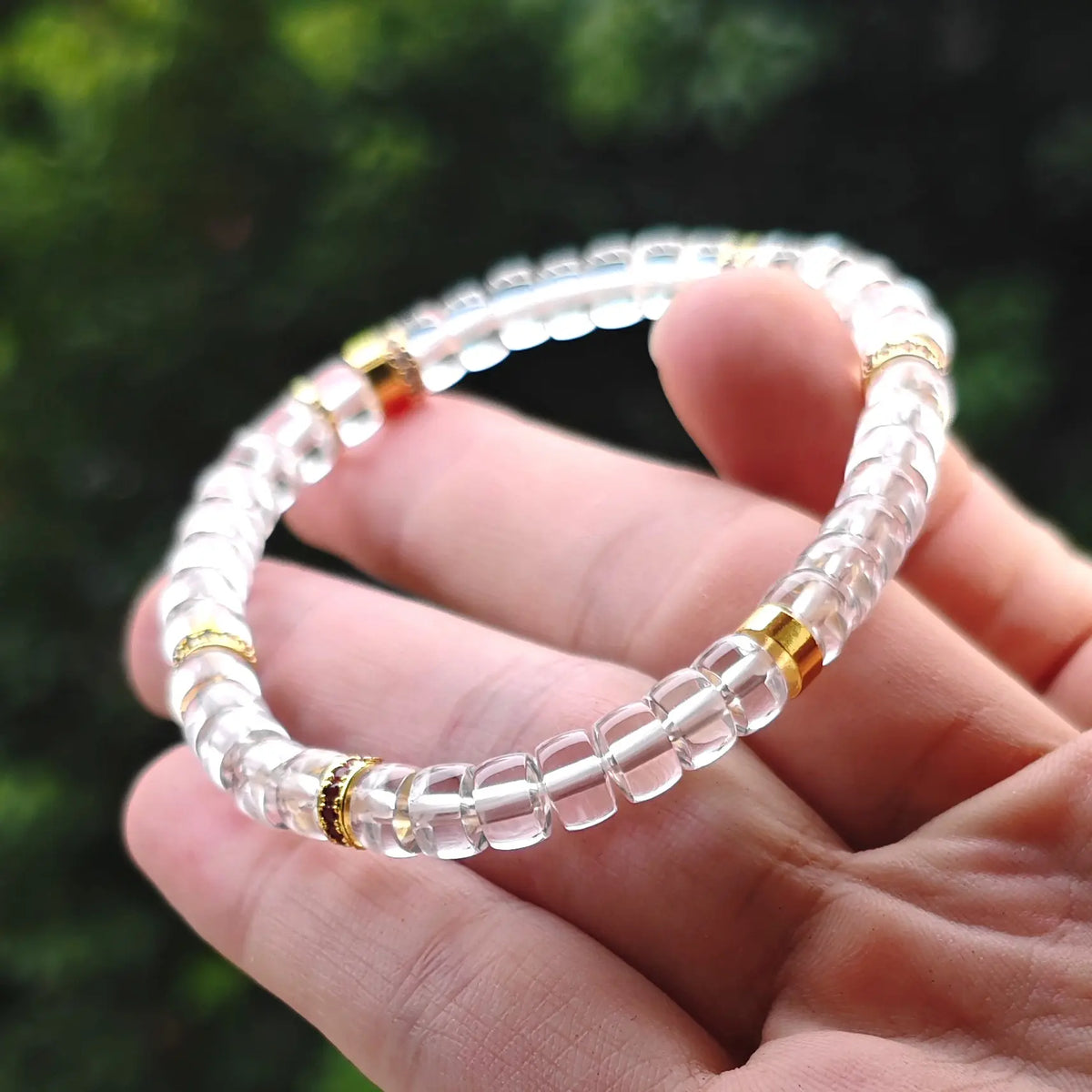 Hand holding a natural clear quartz gemstone bracelet featuring copper-tone alloy spacers for wholesale buyers