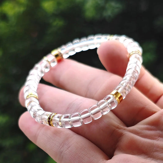 Hand holding a natural clear quartz gemstone bracelet featuring copper-tone alloy spacers for wholesale buyers