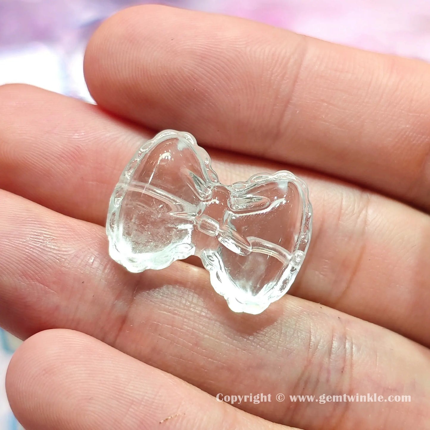 Close up details of natural clear quartz butterfly ribbon bead showing glossy polished surfaces on hand