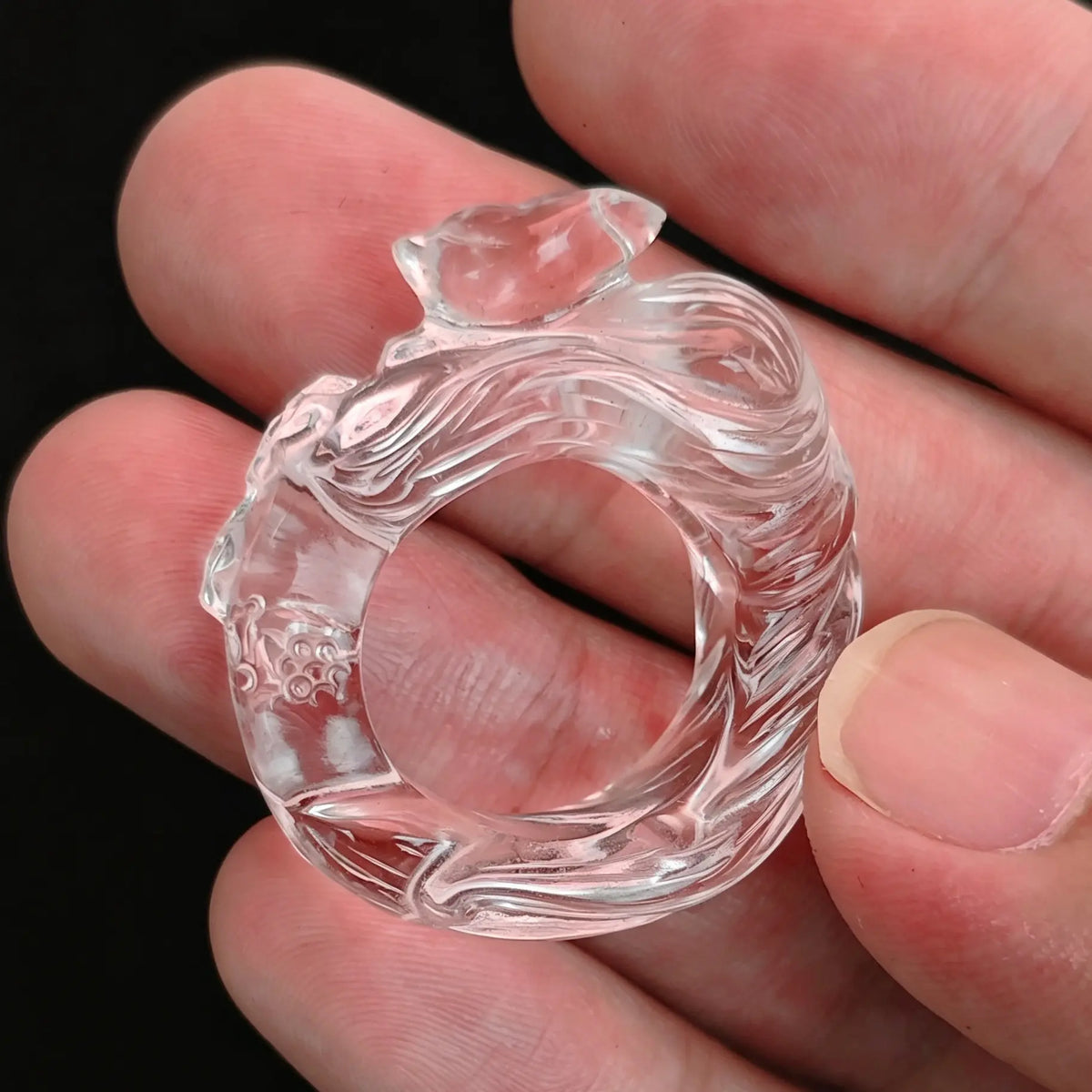Clear quartz carved fox ring held between fingers showing detailed sculpted fox and high transparency