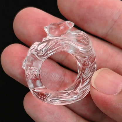 Clear quartz carved fox ring held between fingers showing detailed sculpted fox and high transparency