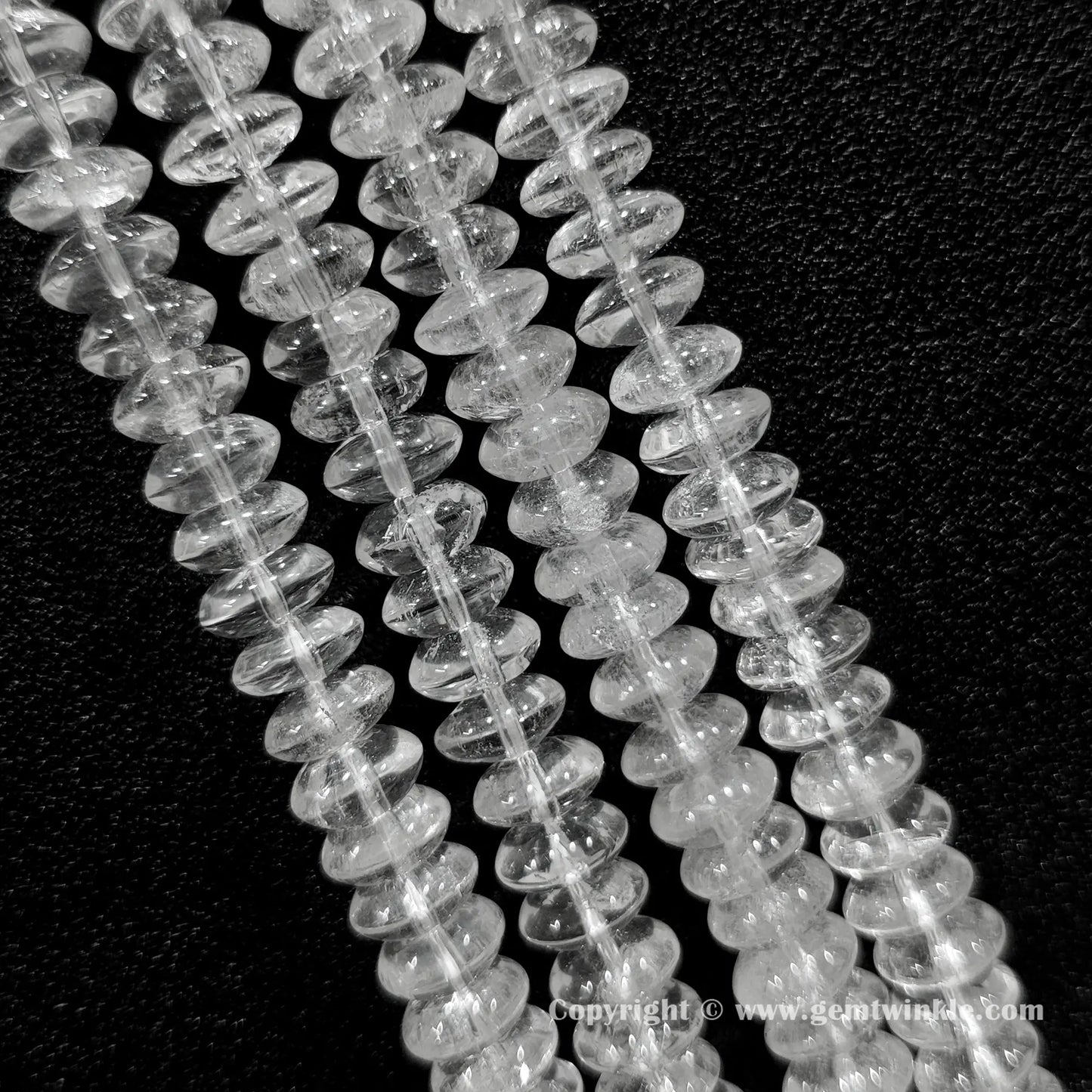 Natural clear quartz rondelle bead strand held over hand showing size scale