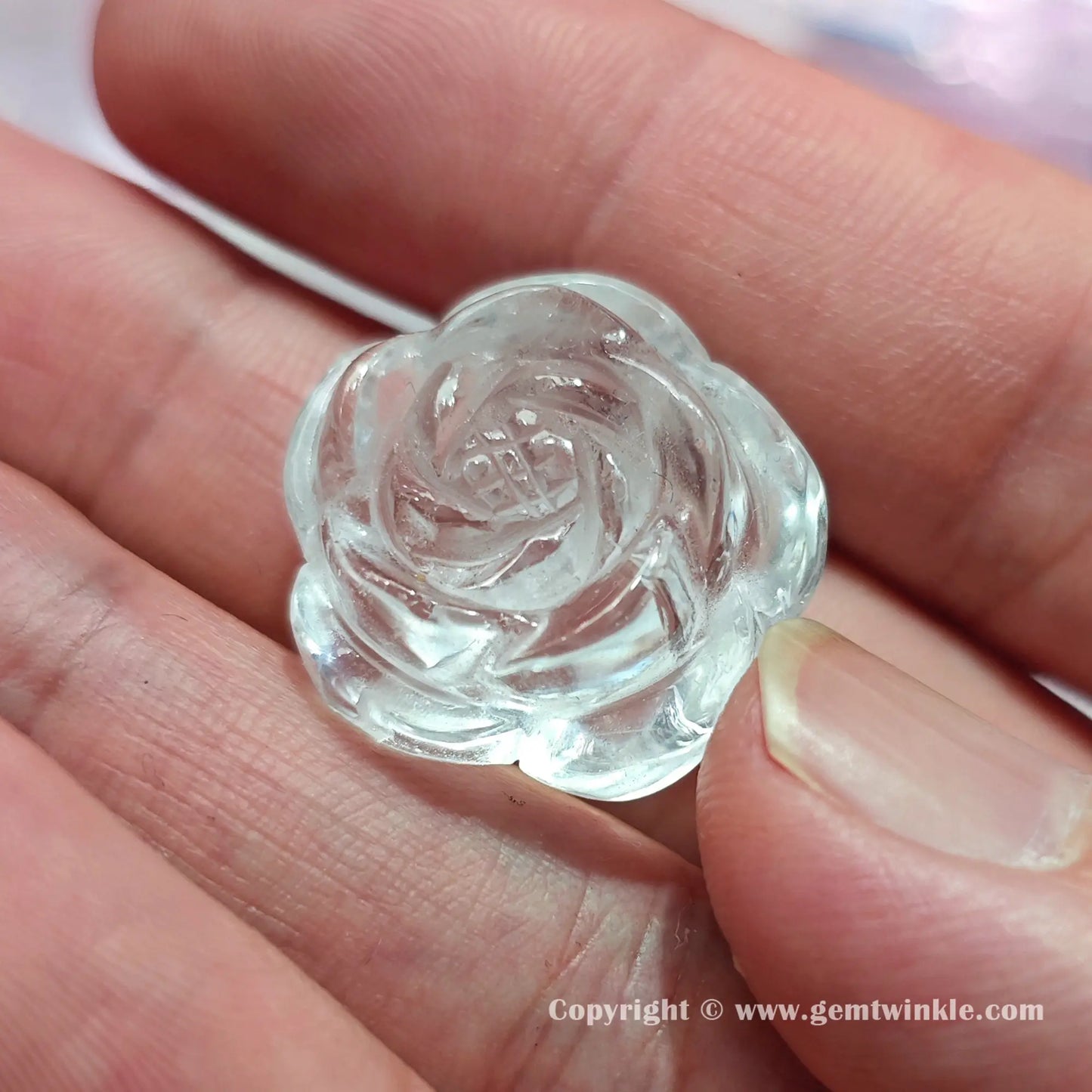 Close up details of natural clear quartz floral carving rose bead showing glossy polished surfaces on fingers