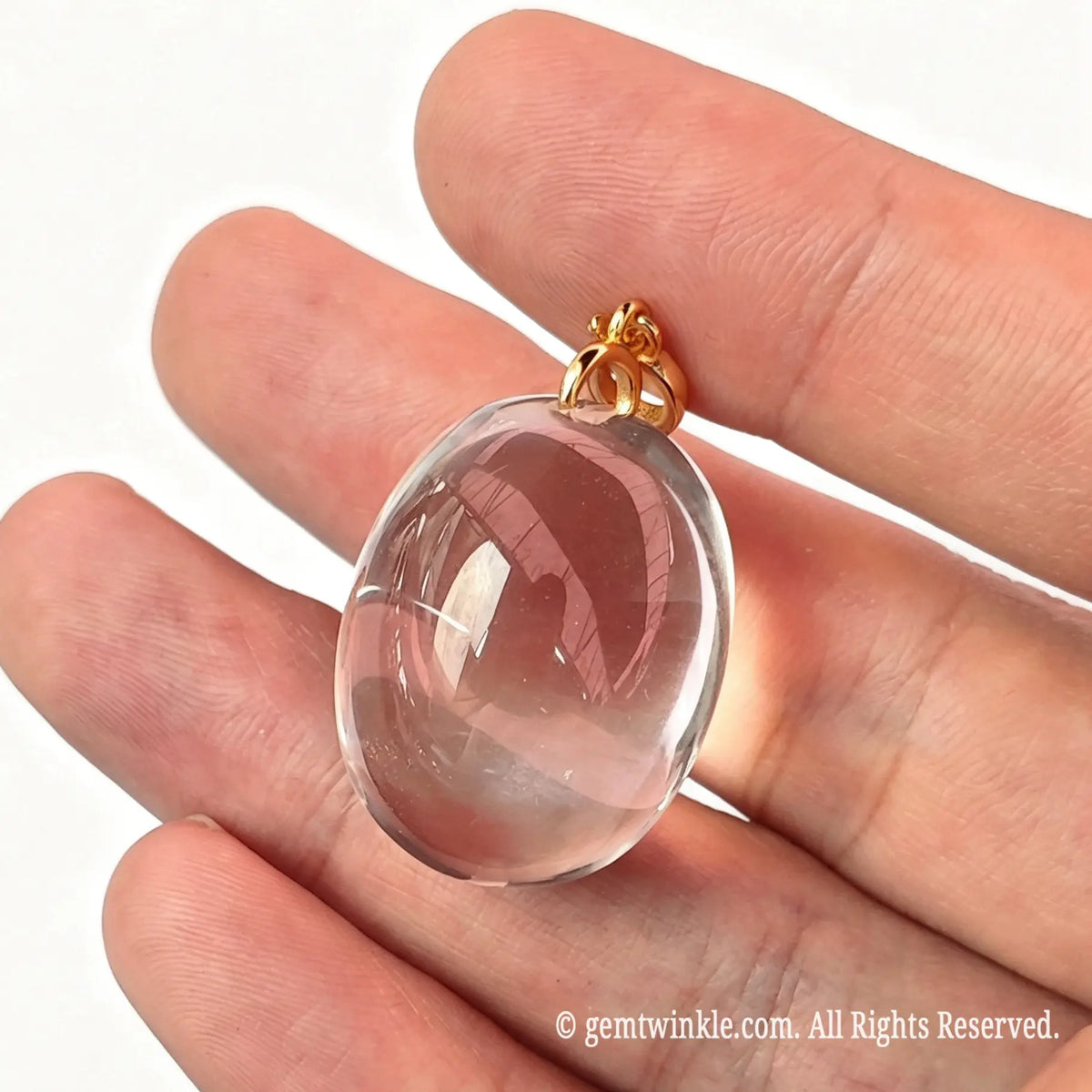 Hand preview of a ~25mm clear quartz oval pendant highlighting pristine stone clarity