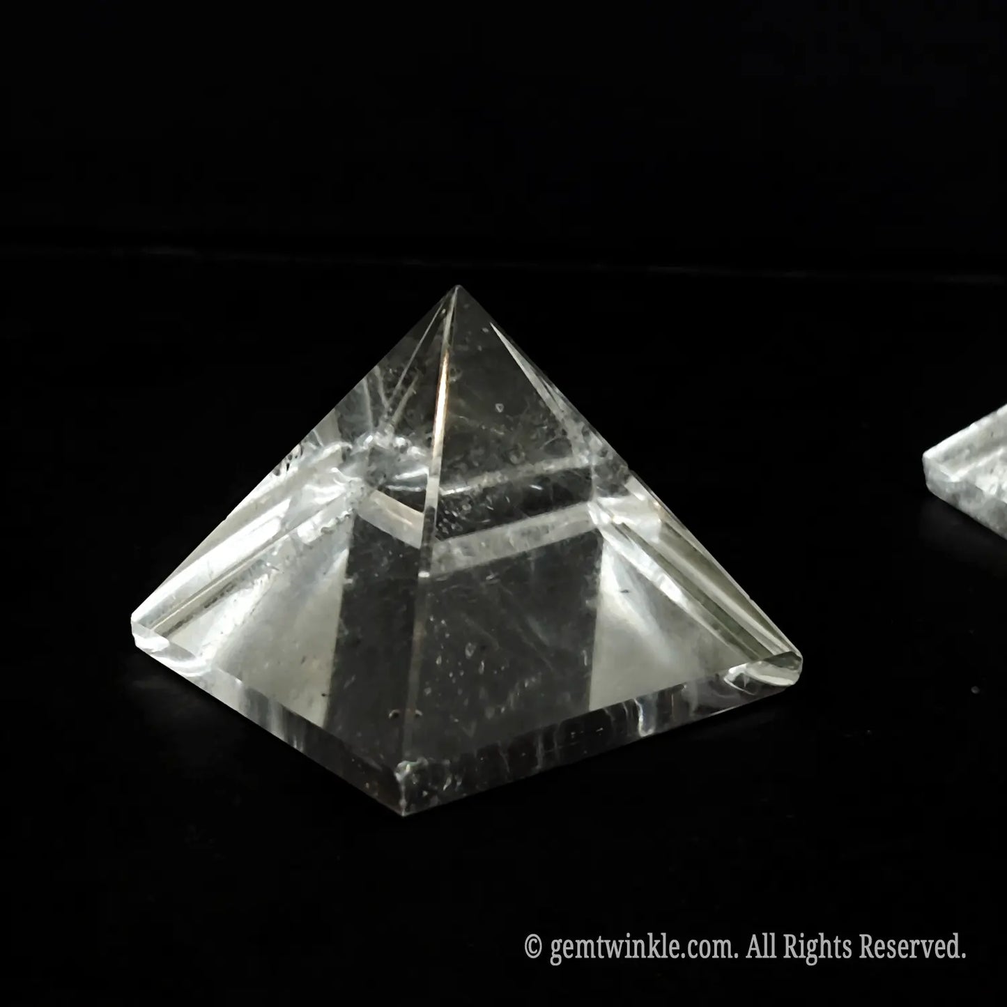 Single 4cm clear quartz pyramid held up to reveal distinct natural ice fractures and inclusions