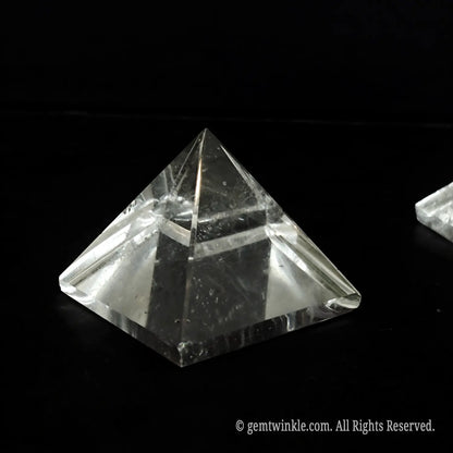 Single 4cm clear quartz pyramid held up to reveal distinct natural ice fractures and inclusions
