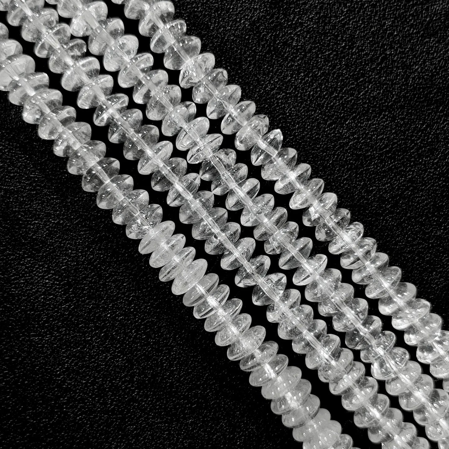 Macro closeup of natural clear quartz rondelle disc beads showing internal ice cracks and cotton-like veils