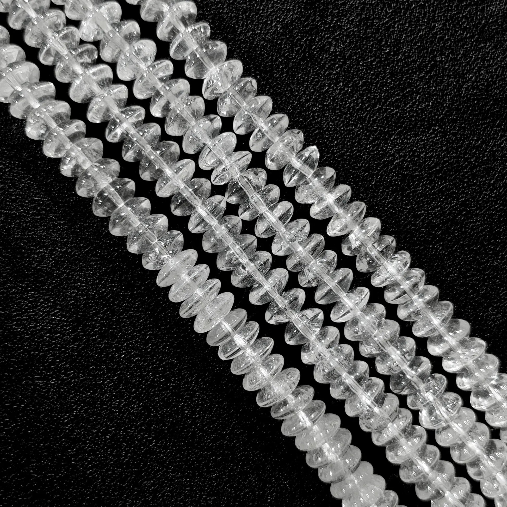 Macro closeup of natural clear quartz rondelle disc beads showing internal ice cracks and cotton-like veils