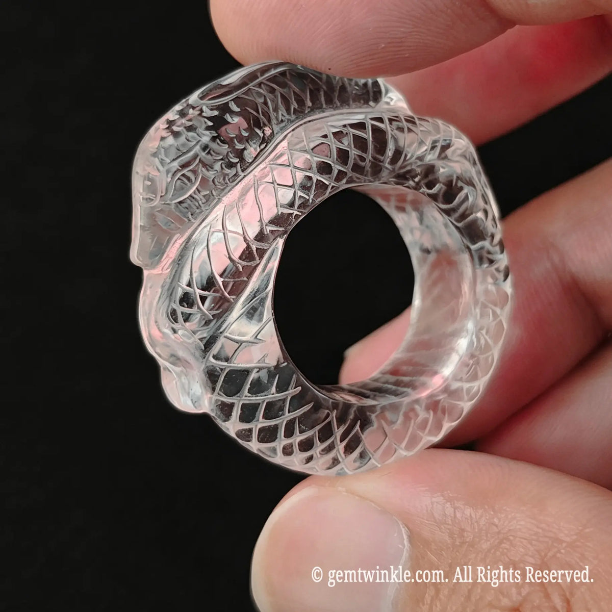 Hand preview of a carved clear quartz snake ring showing ice-like optical clarity and solid gemstone band