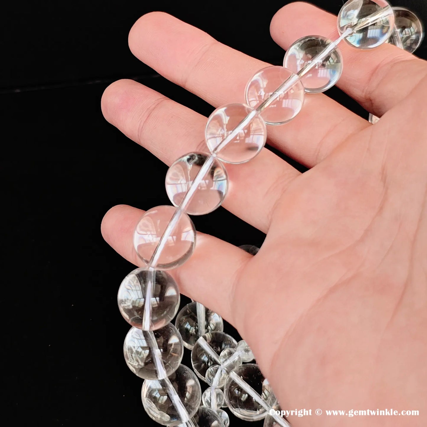 Water-clear rock crystal loose bead strands in palm, premium micro-wholesale gemstone supplies for boutique designers