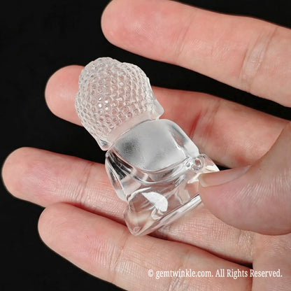 Back view of carved clear quartz buddha figurine held on palm showing smooth polished back and frosted head