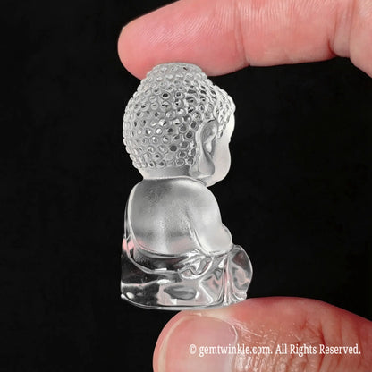 Side view of clear quartz carved buddha figurine showing frosted facial texture and polished crystal body