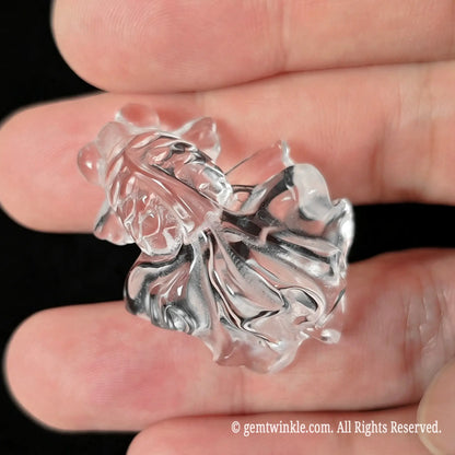 Side view of 30mm clear quartz carved goldfish held in hand showing glass-like clarity and carved tail grooves