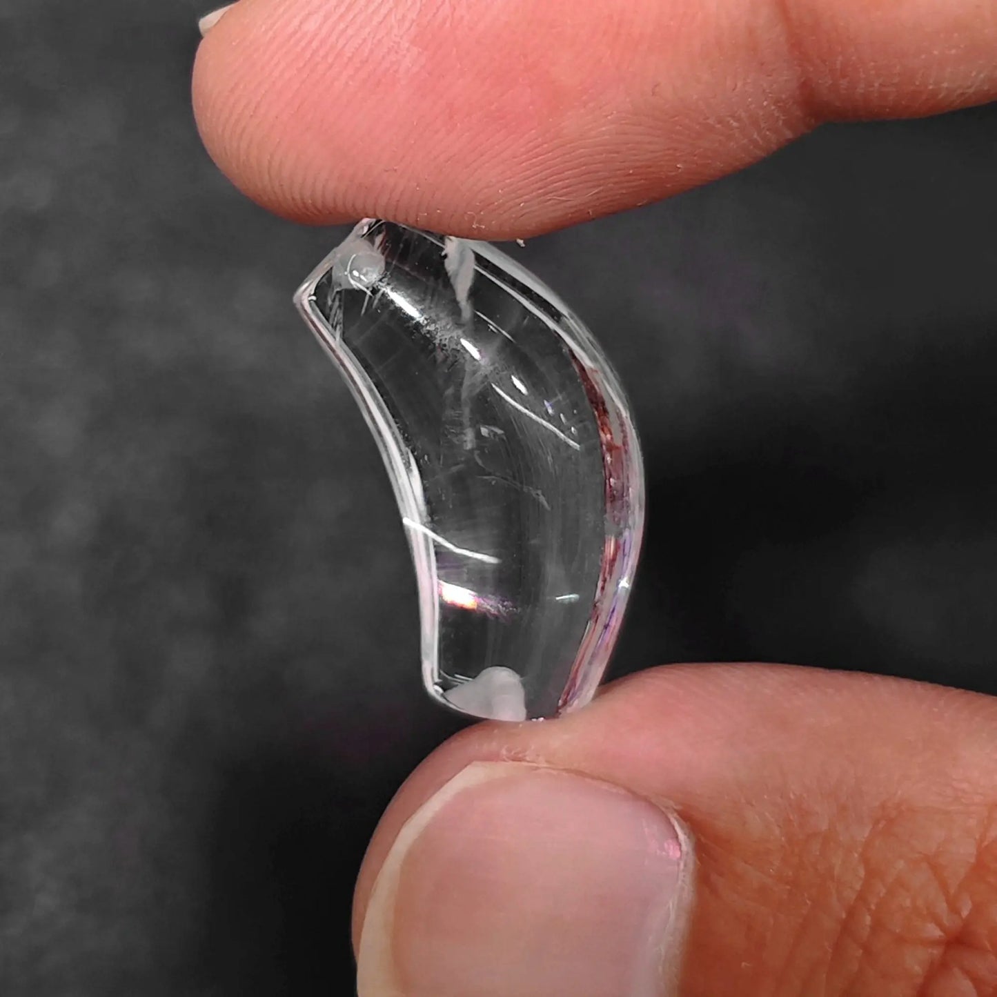 clear quartz curved tube bead with nape drilled hole held between fingers