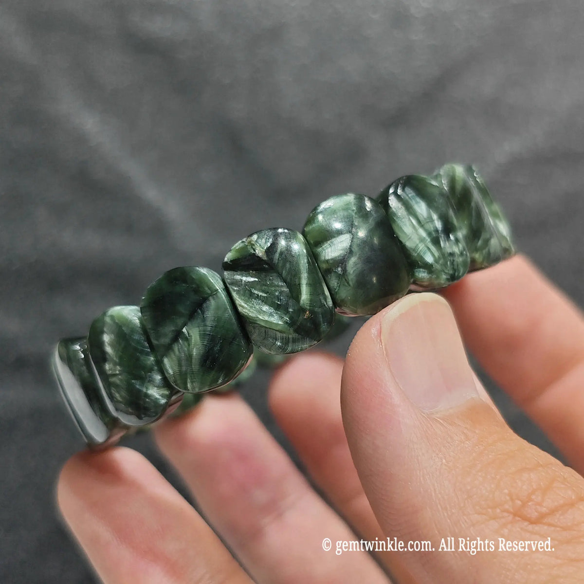 Close up view of clinochlore feather chatoyant wristband showing polished green and silver mineral patterns