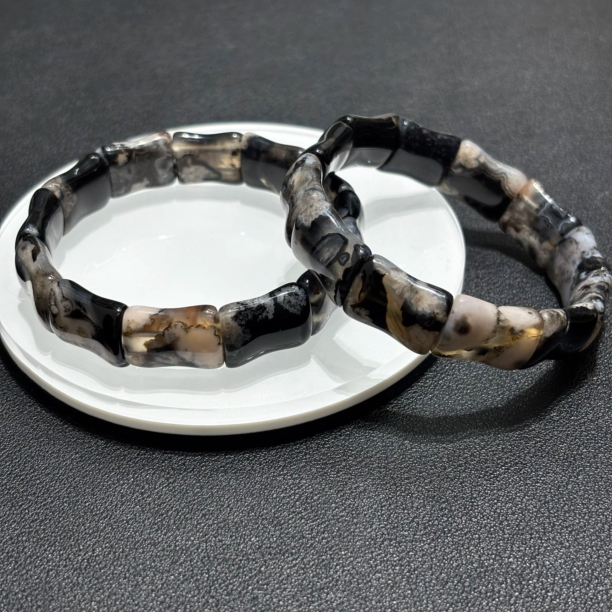 Close up detail of black sakura agate beads with bamboo shape.
