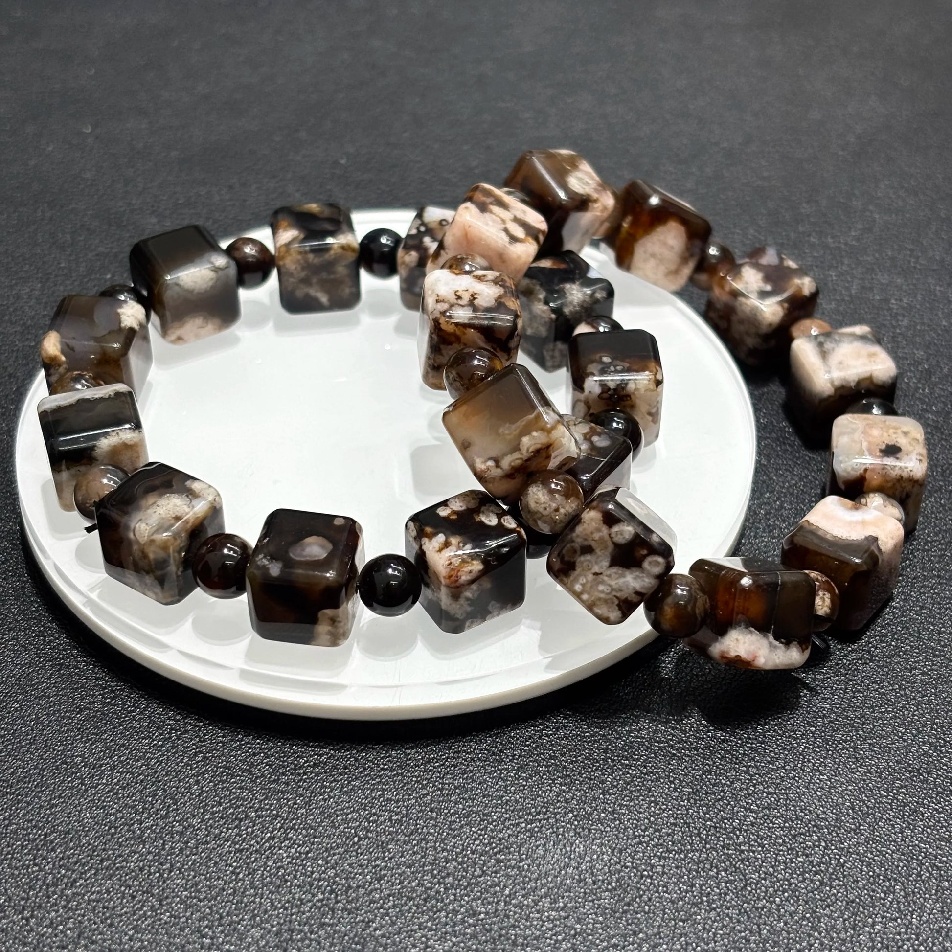 Close-up detail of Black Sakura Agate beads, highlighting the natural stone patterns and cube shape.