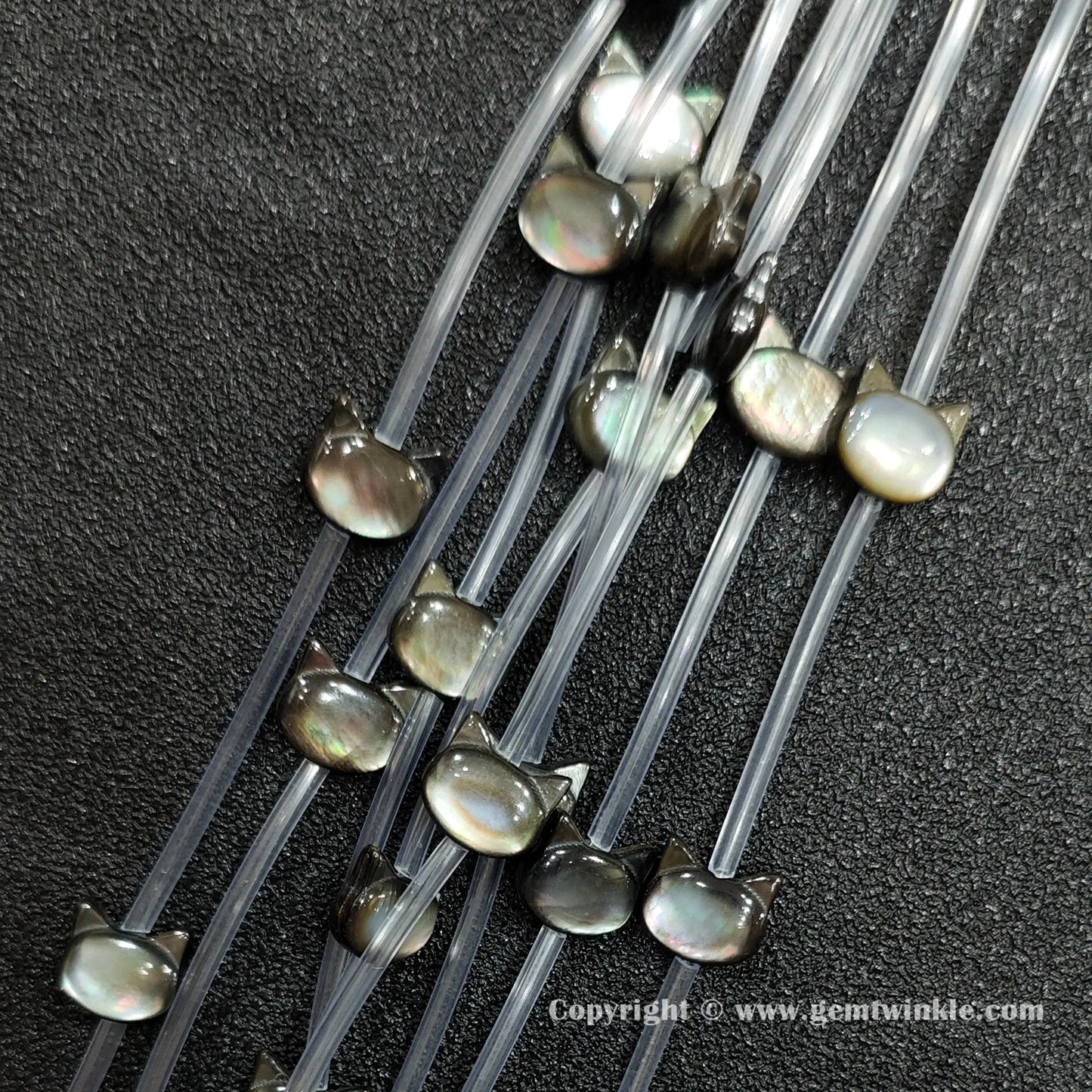 Close up view of carved black shell cat face charms showing ear profile