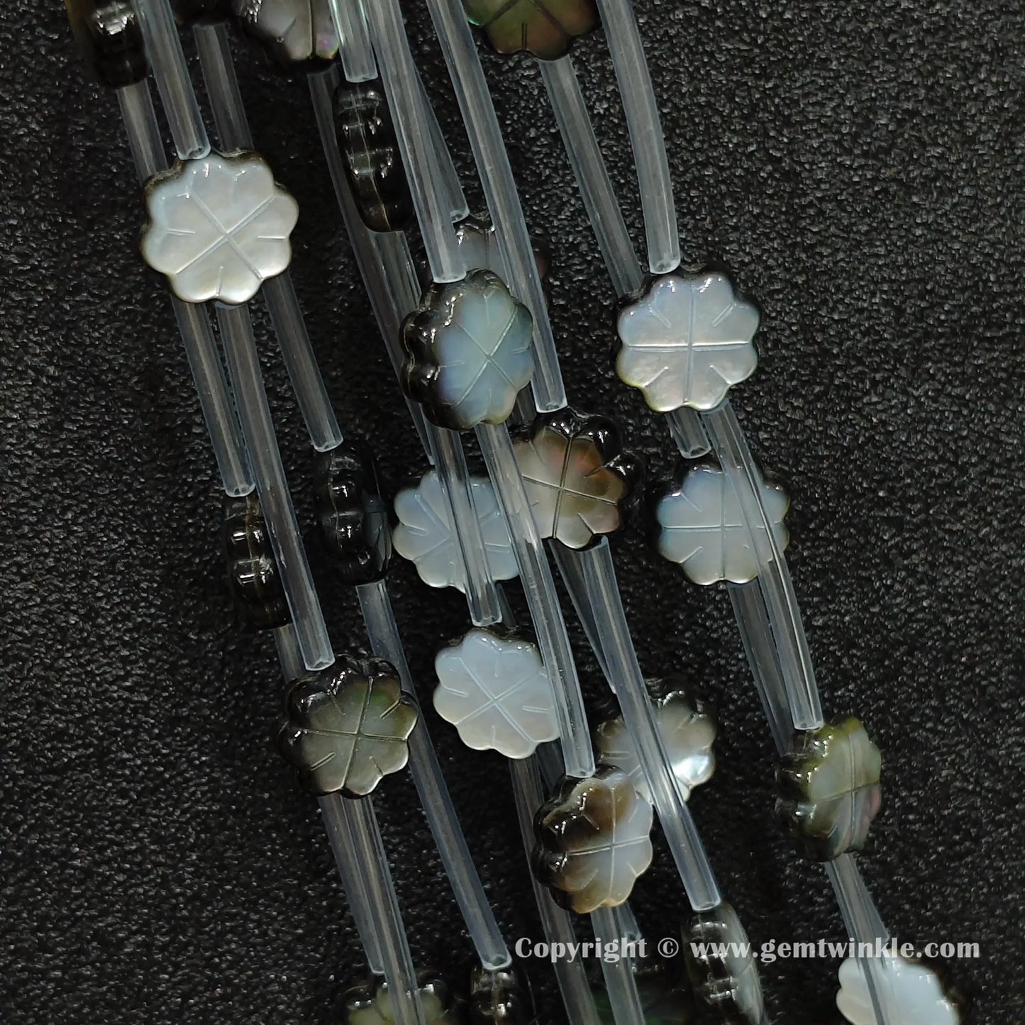 Close up view of carved black shell plum flower charms showing petal relief