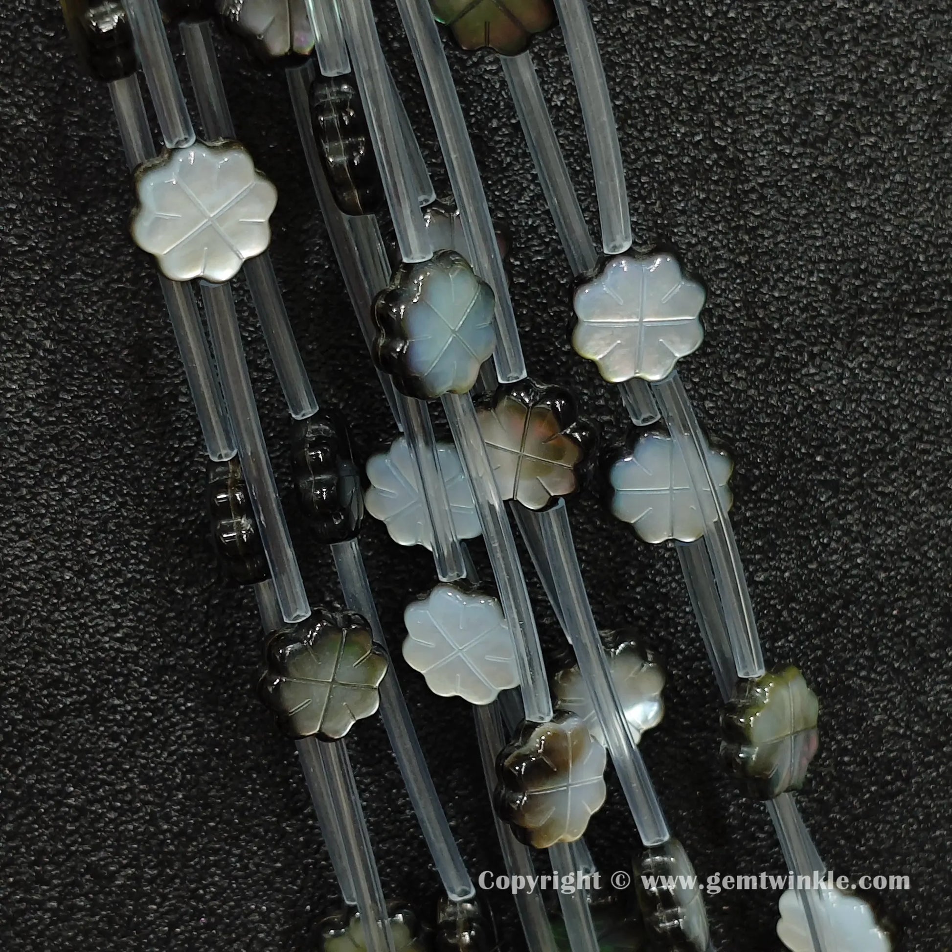 Close up view of carved black shell plum flower charms showing petal relief