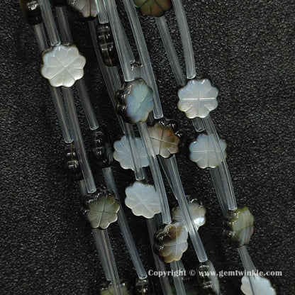 Close up view of carved black shell plum flower charms showing petal relief