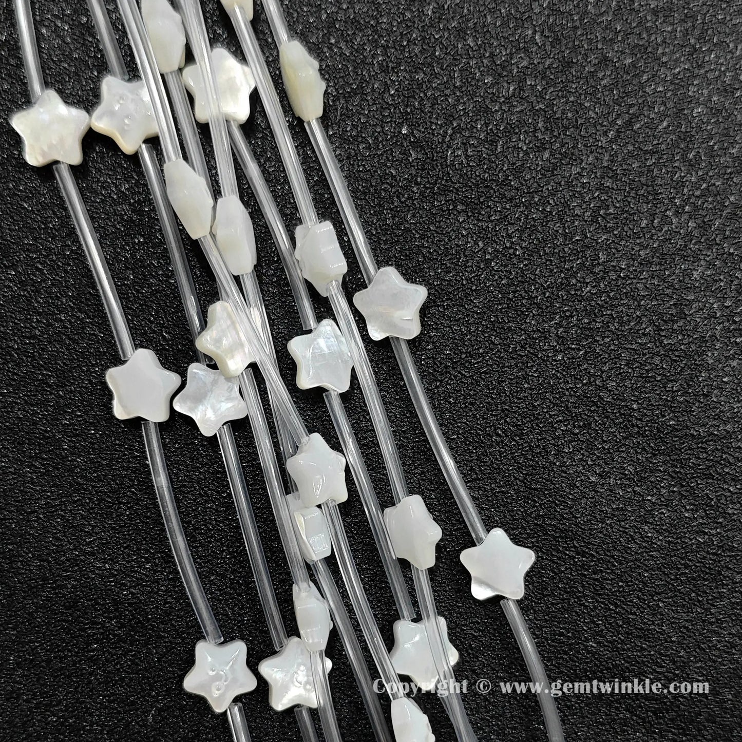 Close up view of carved white shell happy face star charms showing smile relief