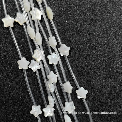 Close up view of carved white shell happy face star charms showing smile relief