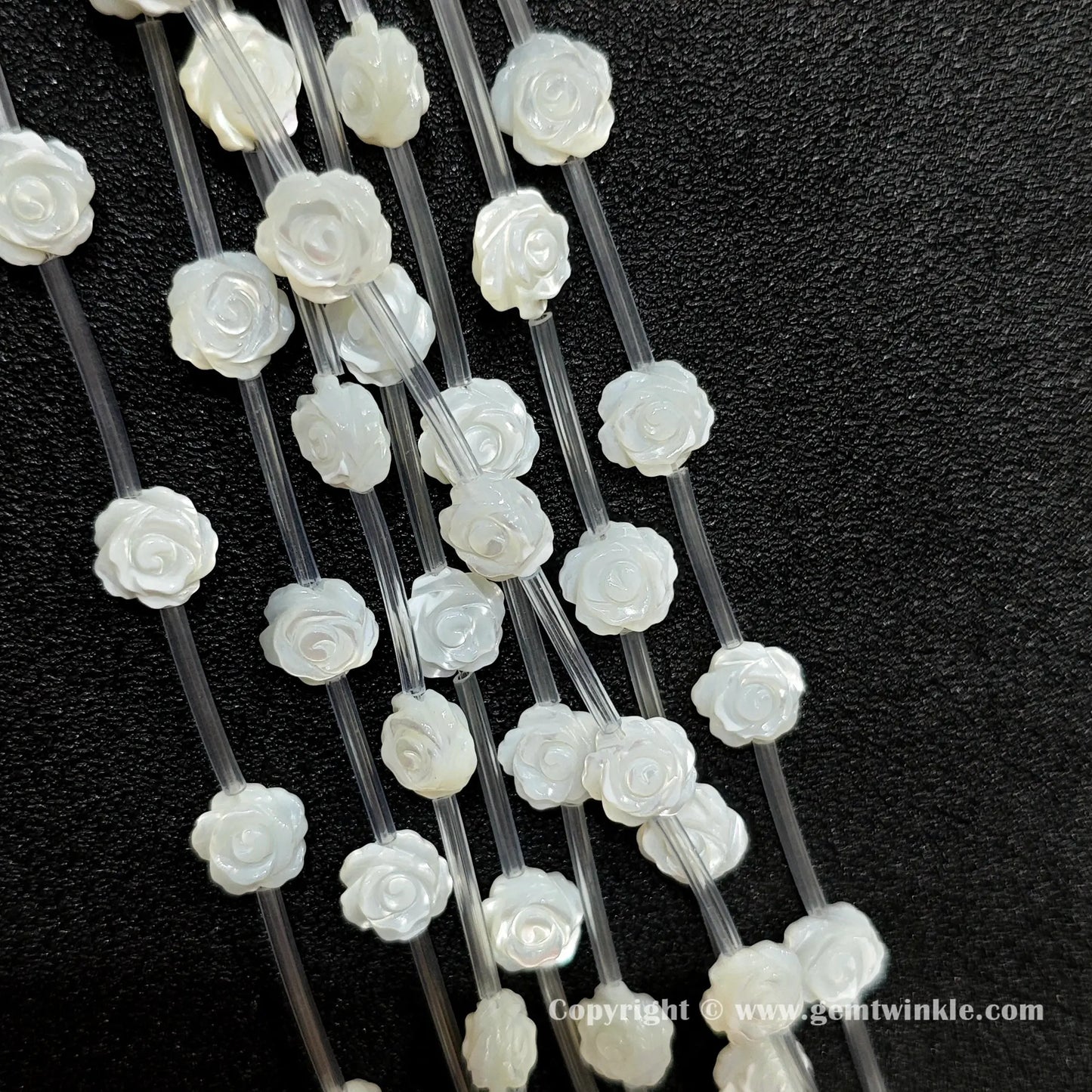 Close up view of carved white shell rose flower beads showing petal detail
