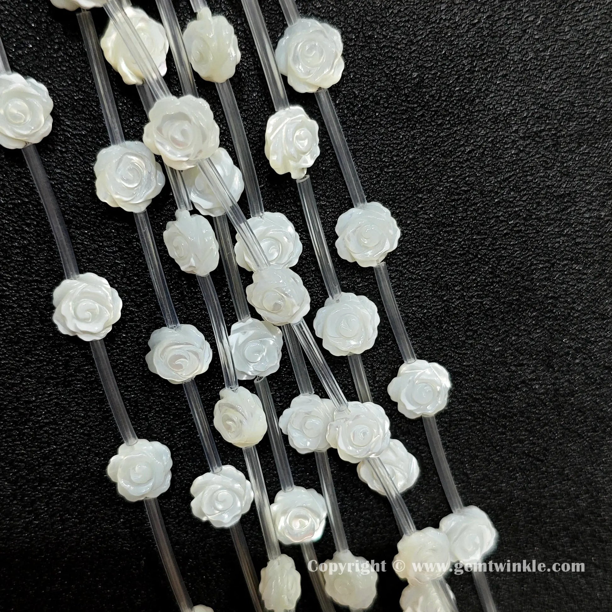 Close up view of carved white shell rose flower beads showing petal detail