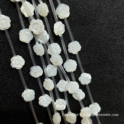Close up view of carved white shell rose flower beads showing petal detail