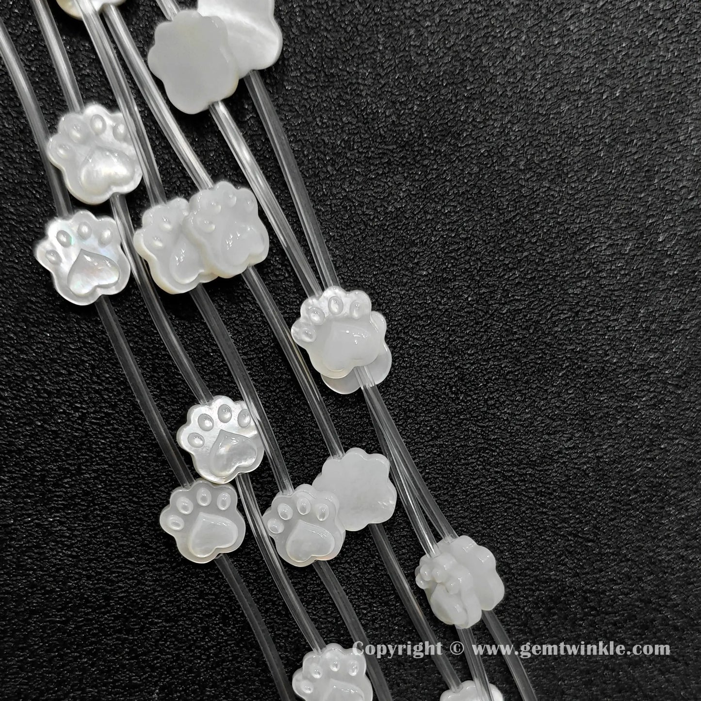 Close up view of carved white shell kitten paw charms showing pad detail