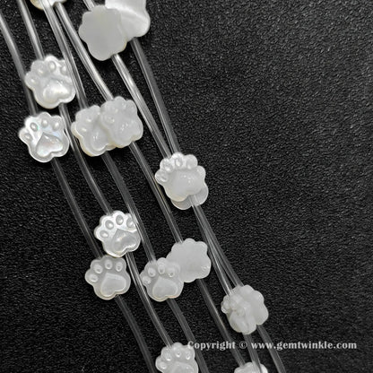Close up view of carved white shell kitten paw charms showing pad detail