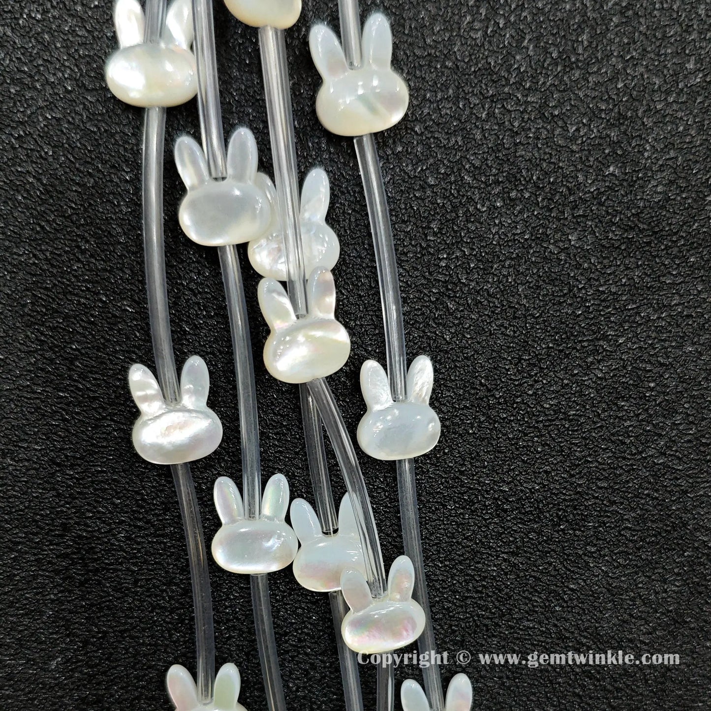 Close up view of carved white shell rabbit charms showing ear profile