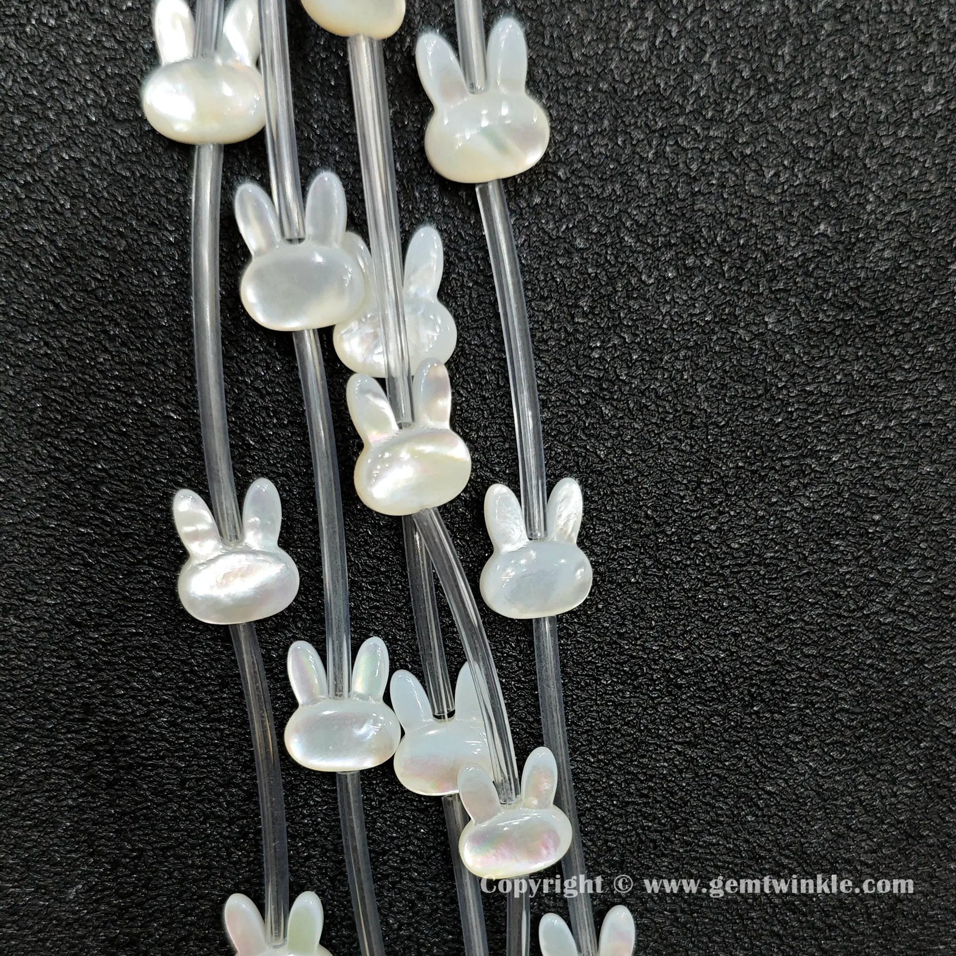 Close up view of carved white shell rabbit charms showing ear profile